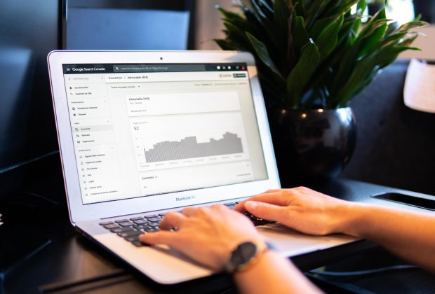 person using macbook air on brown wooden table